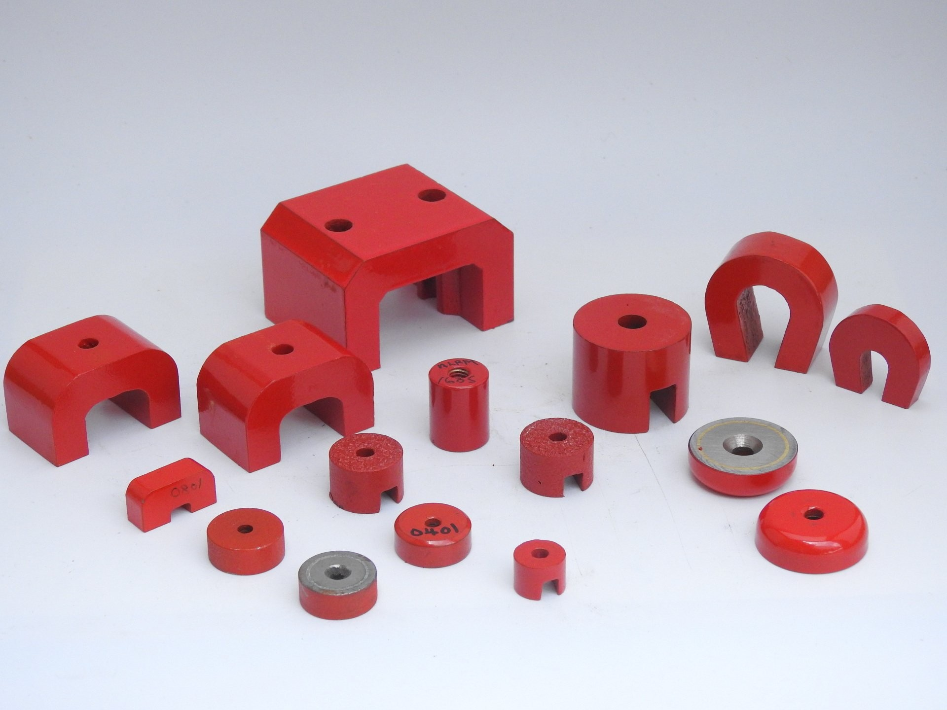 Various types of red industrial magnets used in material handling, separation, and vibration systems